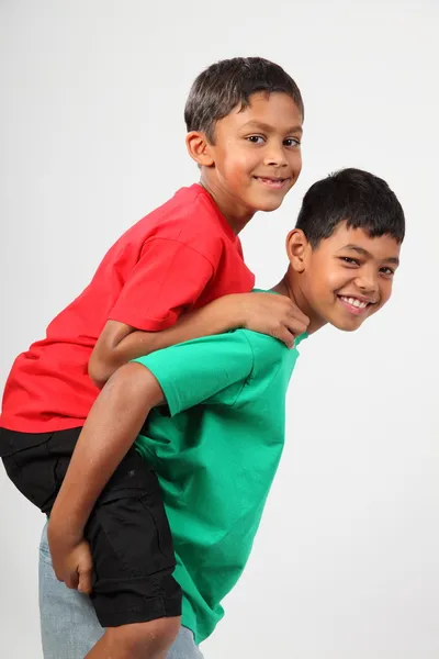 Verspielte junge Schulkameraden geben Huckepack zurück — Stockfoto