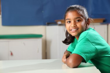 Smiling school girl at class desk