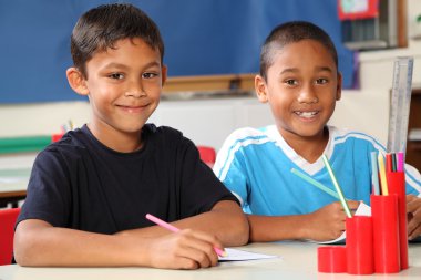 Two happy school boys sitting to their desk in class clipart