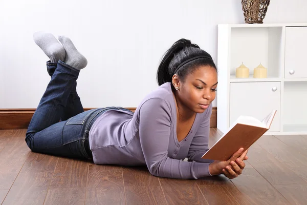 Menina bonita em casa no chão lendo um livro — Fotografia de Stock