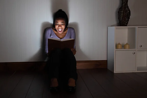 Young woman at home screams reading spooky book — Stock Photo, Image