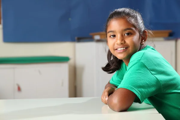 Smiling school girl at class desk — Stok fotoğraf