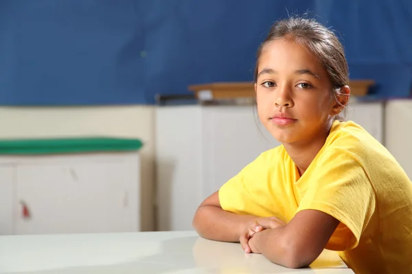 Escola menina 10 braços dobrados em sua mesa de aula — Fotografia de Stock