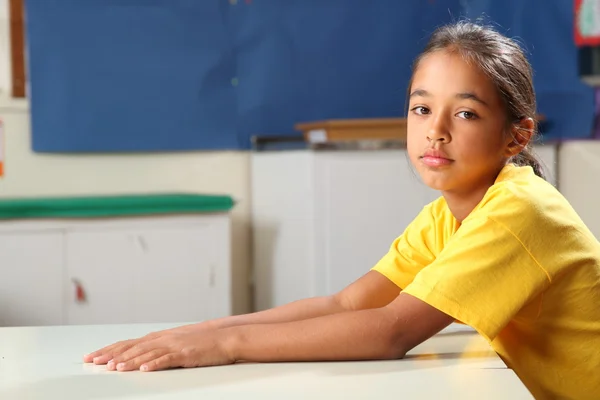 Zasmušilý školačka 10 čekání u stolu učebny — Stock fotografie