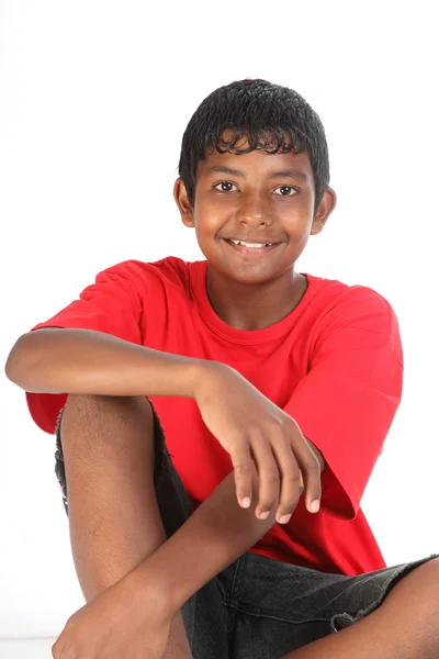 Jeune adolescent souriant assis en studio — Photo