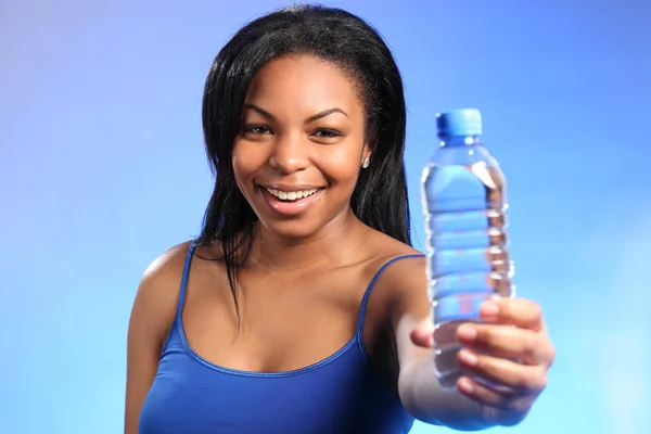 Beautiful girl holding out bottled water to camera — Stock Photo, Image