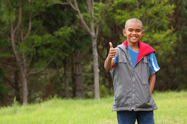 Thumbs up from boy in park — Stock Photo, Image