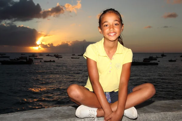 Gün batımında deniz kenarında oturan kız — Stok fotoğraf