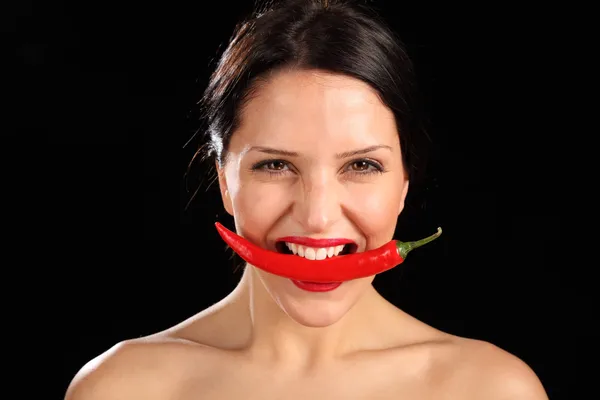 Vacker kvinna biter på röd chilipeppar — Stockfoto