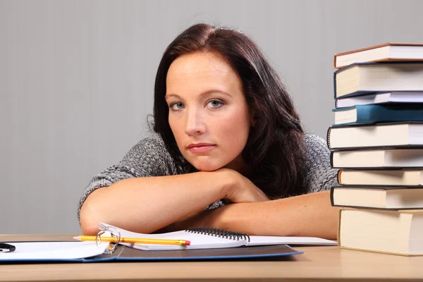 Tired from homework woman rests chin on desk — Stock Photo, Image