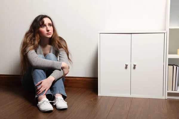 Orolig tonårsflicka sitter ensam på golvet hemma — Stockfoto