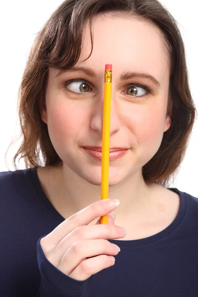 Green cross eyes of girl with pencil on her nose — Stock Photo, Image