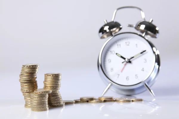 El tiempo es dinero plata reloj despertador y monedas de libra —  Fotos de Stock