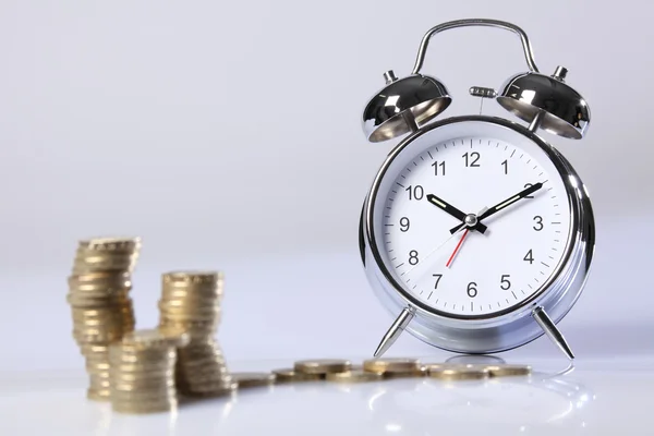 Czas to pieniądz srebrny zegar i złote monety funta — Zdjęcie stockowe
