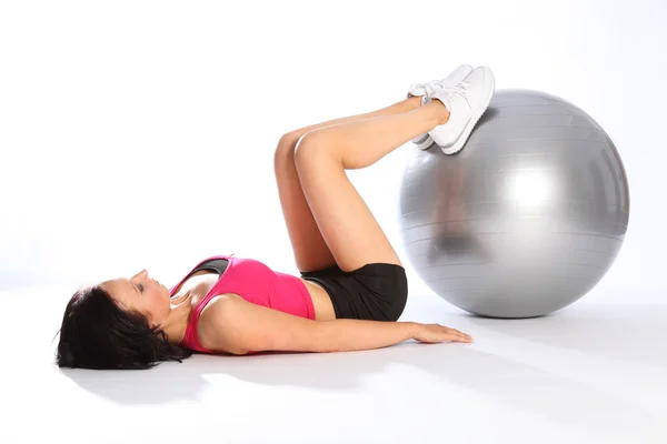 Exercício no chão com bola por mulher bonita no ginásio Fotografia De Stock