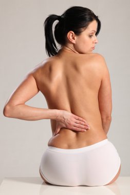 Massage lower back pain for semi nude young woman clipart