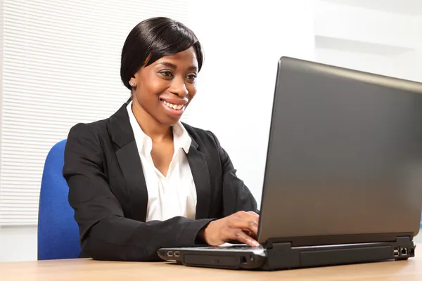 Mulher negra feliz usando laptop na mesa de escritório — Fotografia de Stock