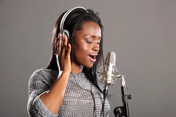 Haciendo música hermosa mujer negra cantando en mic Fotos de stock