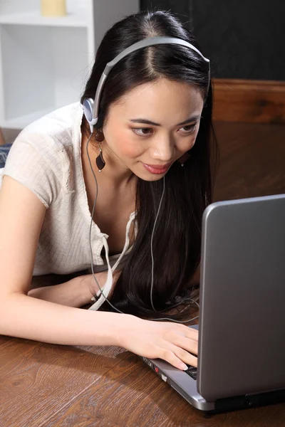 用耳机在笔记本电脑上使用 skype 的亚洲女孩 — 图库照片