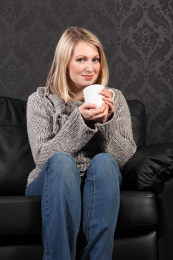 Happy young woman relaxed at home drinking coffee clipart