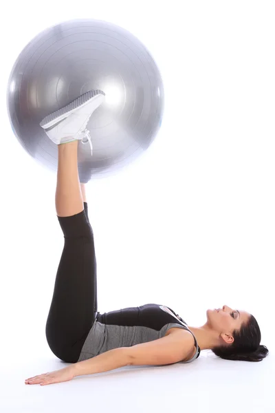 Сильная молодая женщина тренирует ноги с мячом — стоковое фото