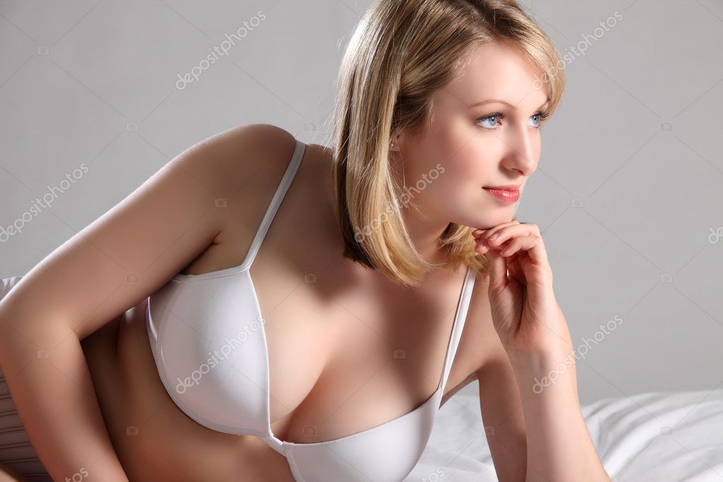 Beautiful blonde woman in bed with sexy cleavage Stock Photo by