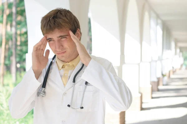 Médico jovem com uma dor de cabeça — Fotografia de Stock