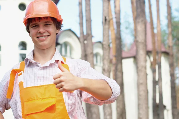 Sonriente joven trabajador con un pulgar hacia arriba al aire libre — Foto de Stock