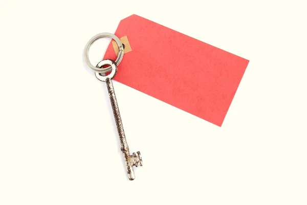 Old long silver door key attached to message label — Stock Photo, Image