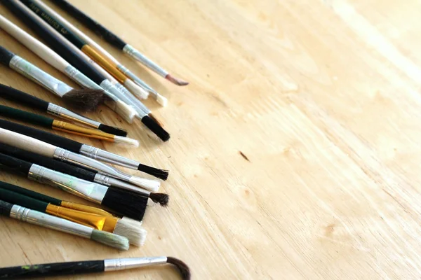 Mixed artists paint brushes on pine table with space — Stock Photo, Image