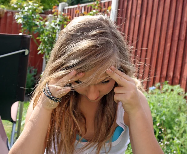 Mooie tiener meisje in de tuin met hoofdpijn — Stockfoto