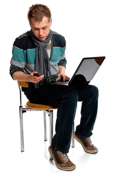 Młody człowiek z laptopem i telefonem komórkowym — Zdjęcie stockowe