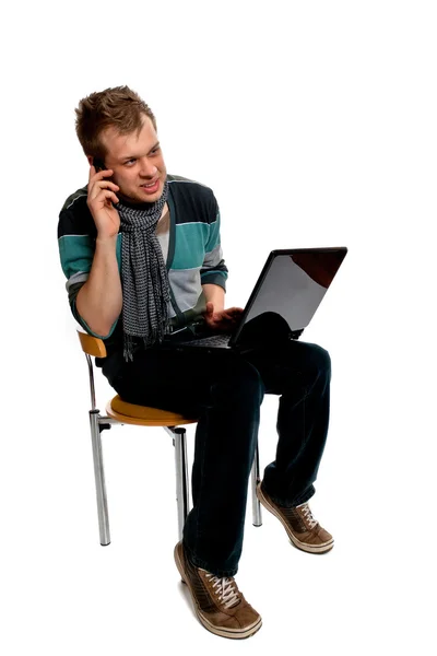 Młody człowiek z laptopem i telefonem komórkowym — Zdjęcie stockowe