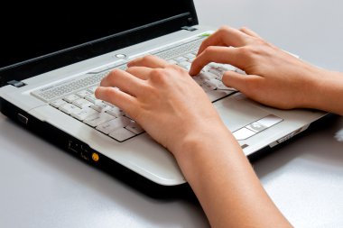 Women's hands close-up on the laptop keyboard clipart