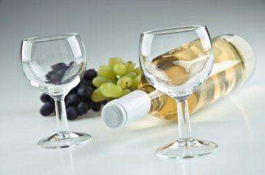 Bottle of white, two empty glasses and grapes clipart