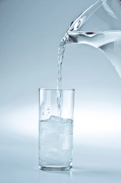 Water being poured from the pitcher to the glass — Stock Photo, Image