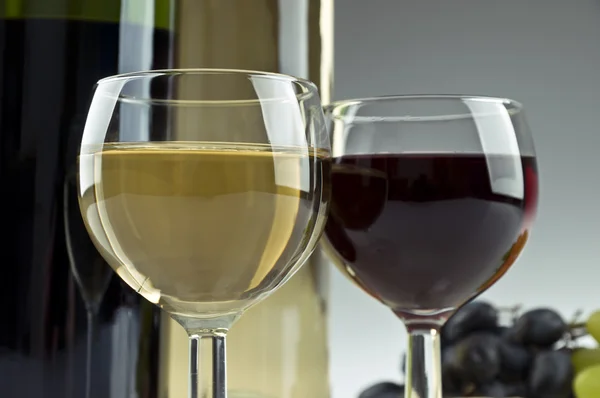 Two bottles of white and red wine, two glasses and grapes — Stock Photo, Image