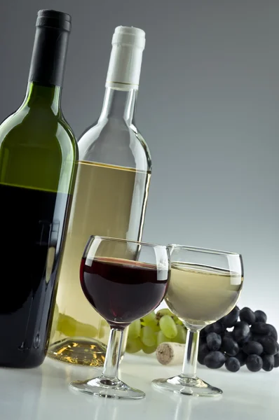 Two bottles of white and red wine, two glasses and grapes — Stock Photo, Image
