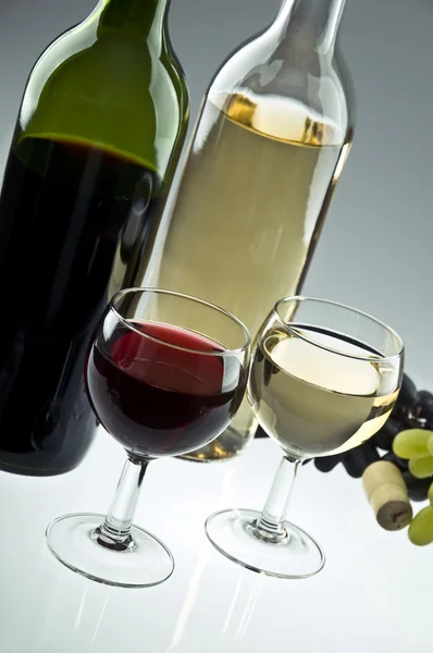 Duas garrafas de vinho branco e tinto, dois copos e uvas — Fotografia de Stock