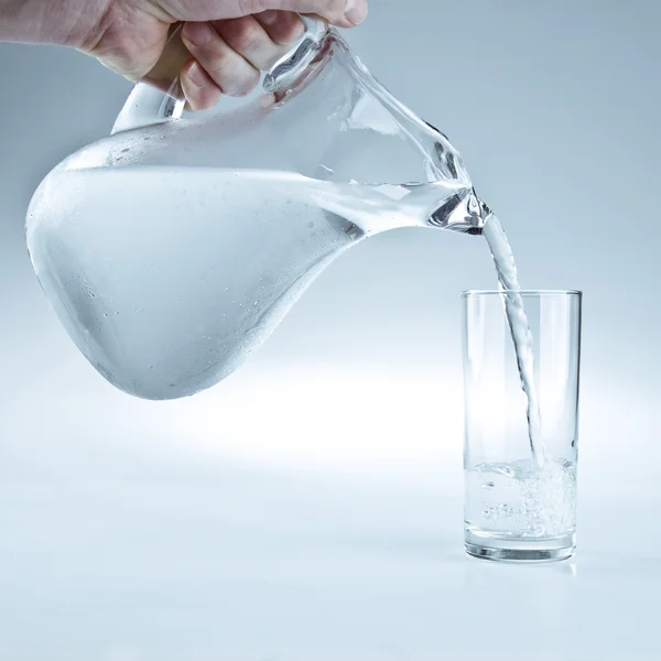 Water being poured from the pitcher to the glass — Stock Photo, Image