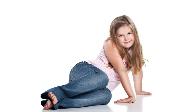 Портрет милої щасливої дівчинки, що сидить на підлозі, ізольовано над білим — стокове фото
