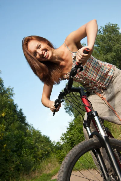Portrait of pretty young woman with bicycle in a park smiling — Stock Photo, Image