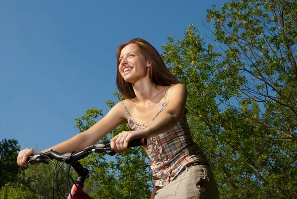 Porträt einer hübschen jungen Frau mit Fahrrad in einem Park lächelnd — Stockfoto