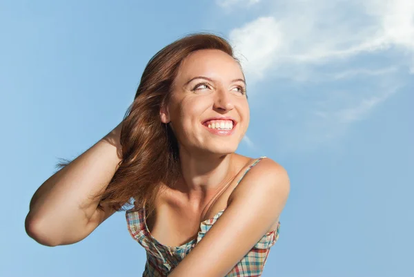 Portret van een mooie jonge vrouw die lacht tegen de hemel — Stockfoto