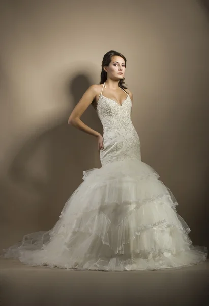 Den vackra unga kvinnan poserar i en bröllopsklänning — Stockfoto