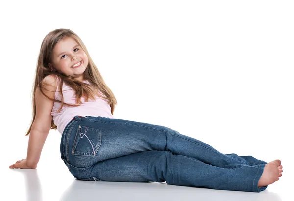 Niedlich glücklich kleines Mädchen sitzt auf weißem Hintergrund — Stockfoto