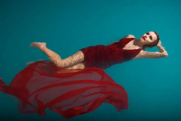 Donna sexy galleggiante sulla piscina in abito rosso — Foto Stock