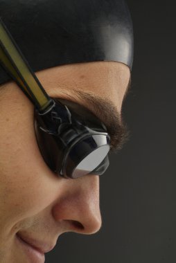 A male swimmer with a swimming hat and goggles ready to jump in the pool clipart