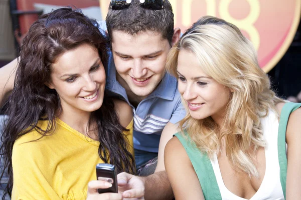 Grupo de amigos lendo mensagem em um telefone celular — Fotografia de Stock