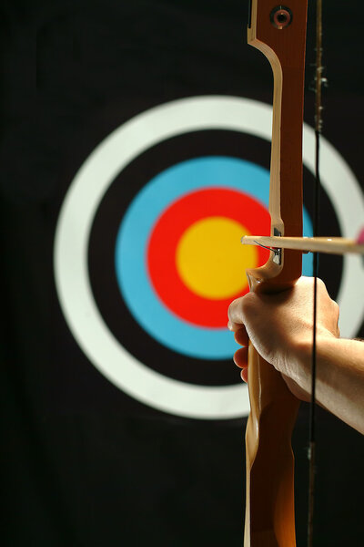 Young man holding bow and shooting to target